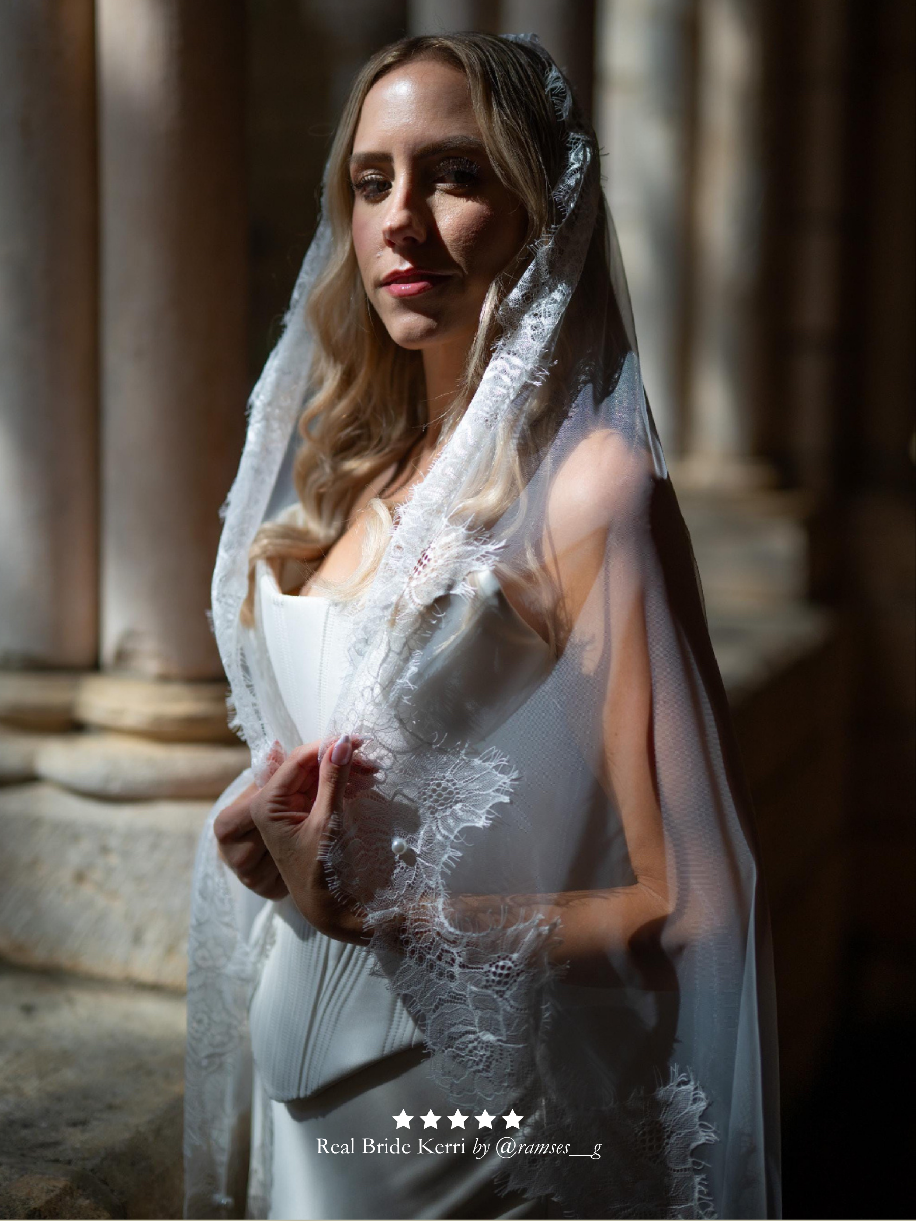 Woman in a corset wedding dress with a Chantilly lace mantilla veil standing in front of stone columns. With five star review overlay.