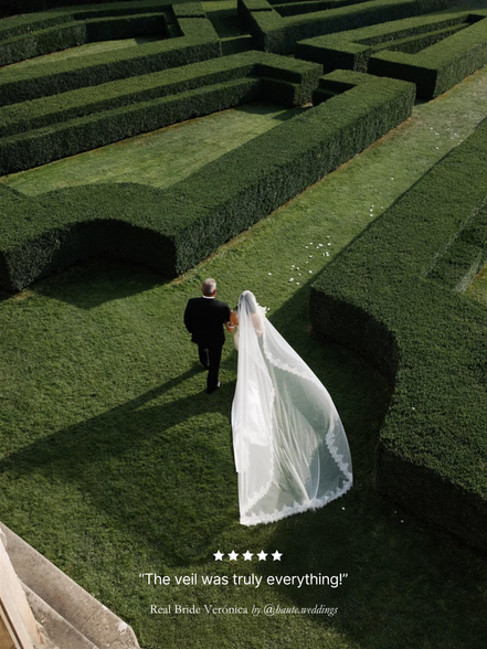 Man and woman walking through a hedge maze with a long, extra wide chantilly lace mantilla veil trailing behind. With five star review overlay.