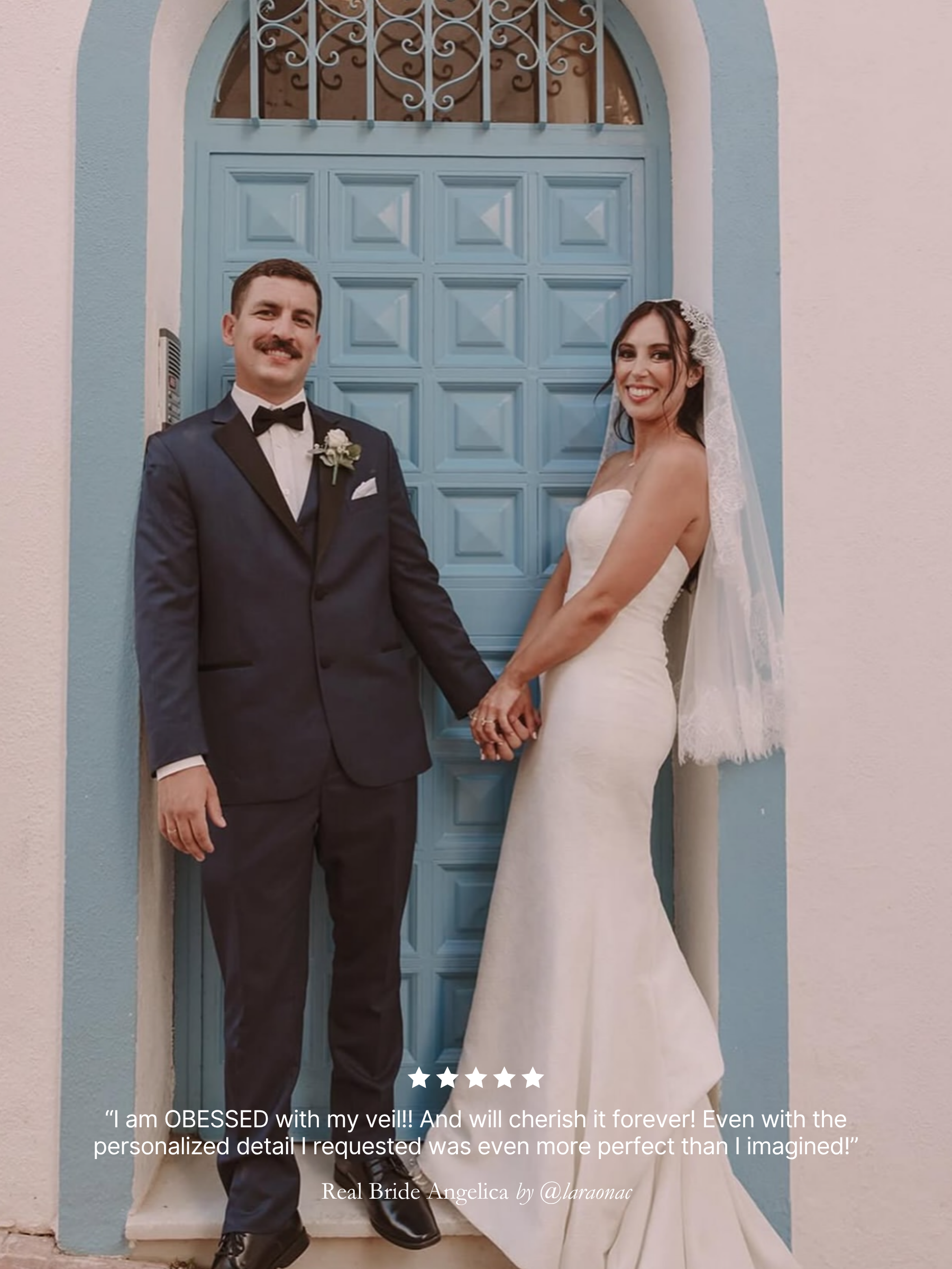 Man and woman in wedding attire standing in front of a blue door. Featuring her custom chantilly lace short mantilla veil by Harriett Falvey