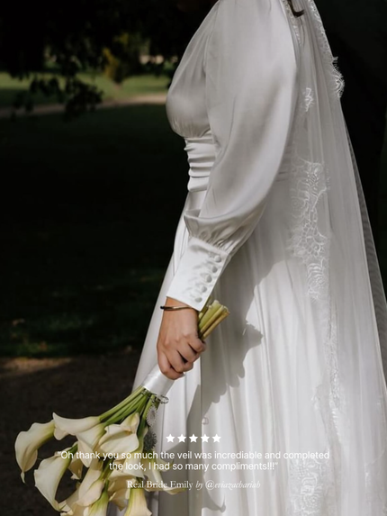 Bride in a white wedding dress holding a bouquet with a blurred background, featuring her chantilly lace mantilla veil by Harriett Falvey with review overlay