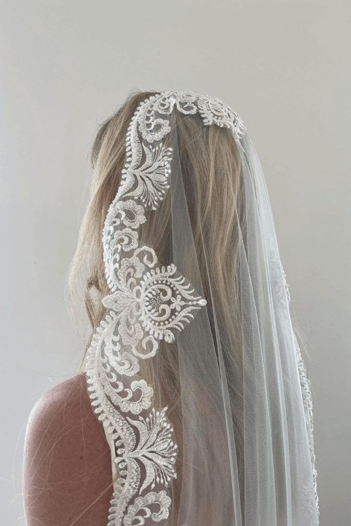 Model styling a Cascading Beaded Lace Mantilla Veil featuring little glass beads and clear sequins.